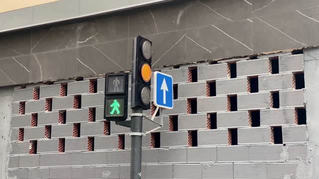 Stoplight next to gray brick wall in the street