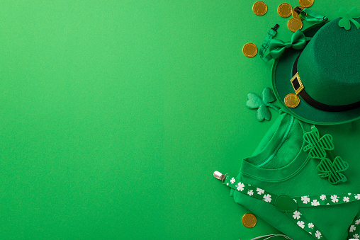 Saint Patrick's Day concept. Top view photo of green shirt clover shaped party glasses leprechaun hat suspenders bow-tie gold coins and shamrocks on isolated green background with copyspace