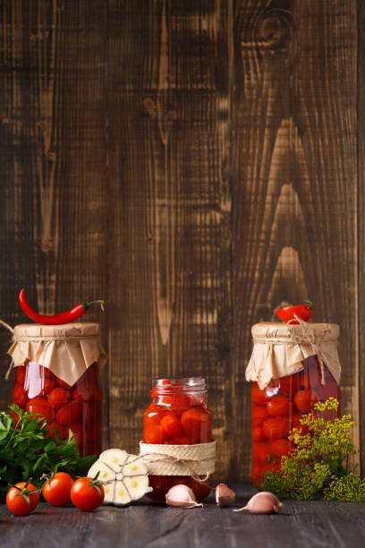 pomidory koktajlowe w puszkach wpadają do słoika na drewnianym tle z miejscem na tekst - cherry tomato tomato sauce isolated close up zdjęcia i obrazy z banku zdjęć
