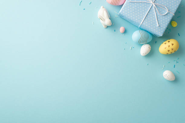 istock Easter decorations concept. Top view photo of blue giftbox with bow colorful eggs ceramic easter bunny and sprinkles on isolated pastel blue background with blank space 1467968962