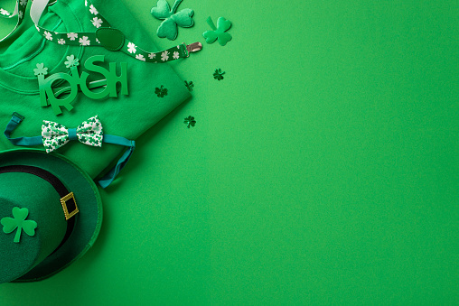 St Patrick's Day celebration concept. Top view photo of green clothing pullover irish party glasses leprechaun hat suspenders bow-tie clovers and confetti on isolated green background with blank space