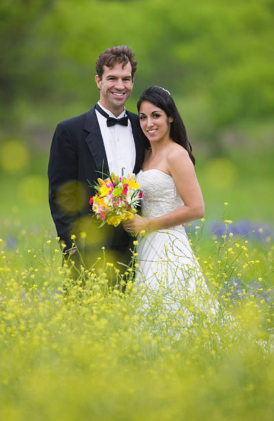 pareja de novios de pie al aire libre en las flores silvestres - bride women standing beauty in nature fotografías e imágenes de stock