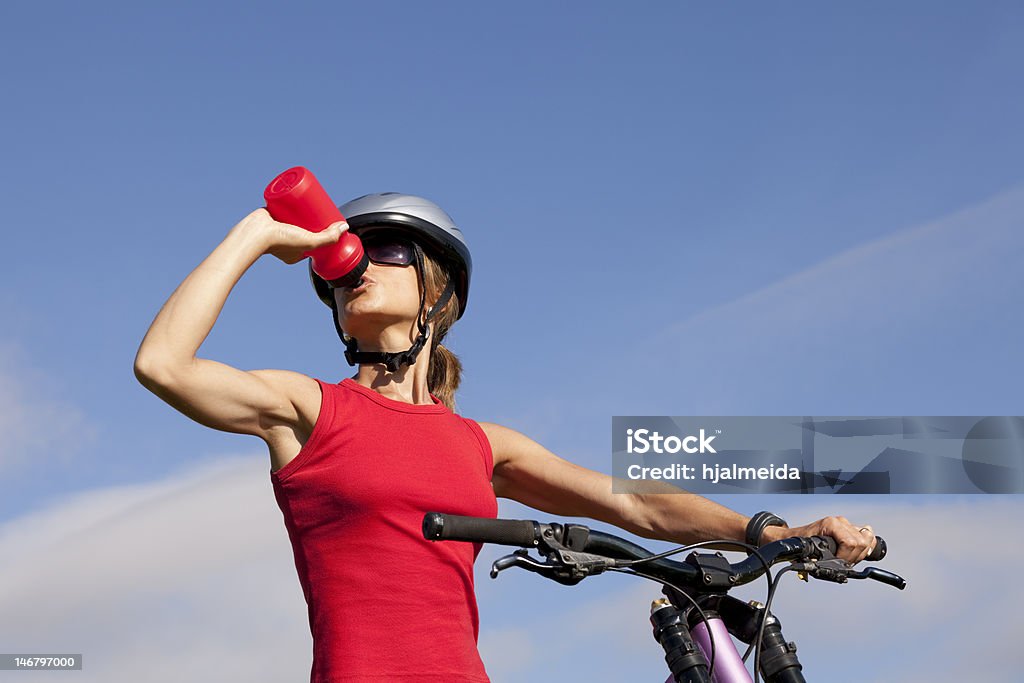 Woman drinking water in her bike Biker woman refreshing drinking water at her morning exercise Cycling Stock Photo