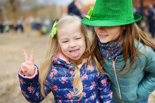 Two cute little girls wearing green hats and accessories celebrating St. Patrick's day in Vilnius. Children having fun at traditional Irish festival.