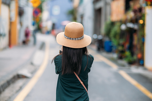 Rear view of a beautiful Asian female tourist with hat exploring the Georgetown, Penang Island, Malaysia
