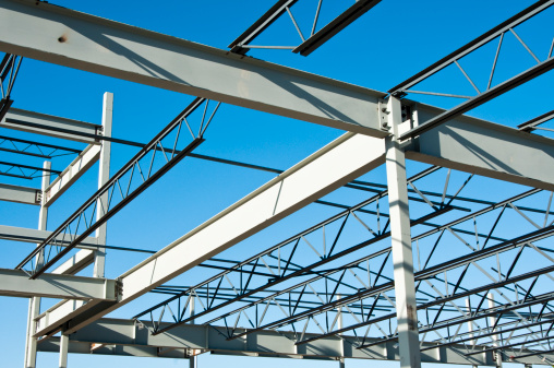 the structural steel structure of a new commercial building against a clear blue sky in the background