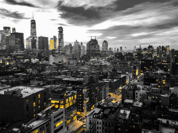 New York City black and white nighttime cityscape with glowing yellow lights in the skyline buildings of downtown Manhattan stock photo