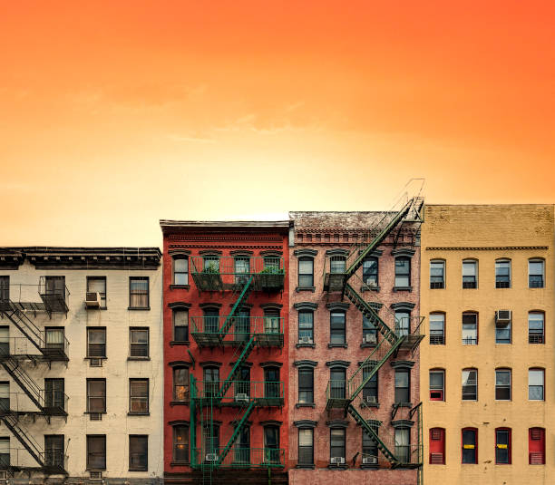 Row of colorful old apartment buildings in Manhattan, New York City with warm yellow orange sunset sky background stock photo