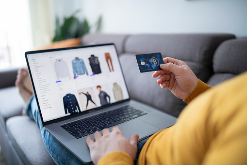 Unrecognizable man shopping online via laptop at home.