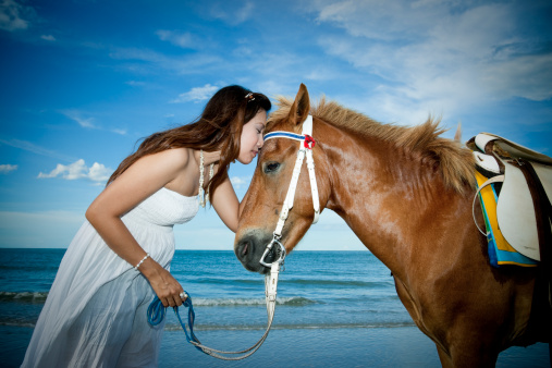Beautiful asian girl on the beach and kissing the horse.