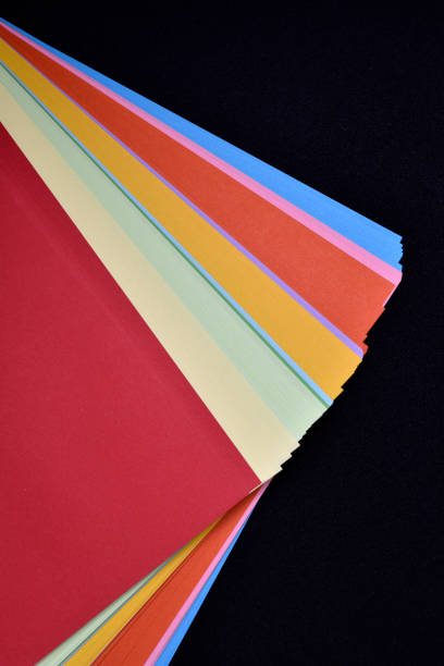 istock Multicolored sheets of paper on a black background. Colored office paper. A pack of colored paper. 1467979587