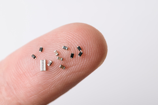 Close up of various micro electronic microchips on human finger.