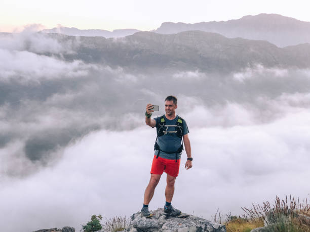 istock Trailrunner active hiker taking a selfie above the clouds at sunrise 1467982771