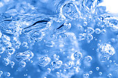 Close up of transparent air bubbles in water in blue tone.
