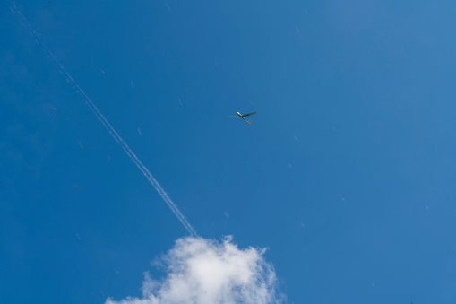 Low angle view of sport plane in flight and vapor trail on blue sky.