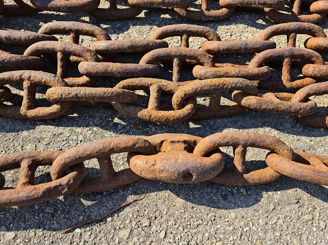 An old rusty anchor chain is laid out on the berth for disposal.