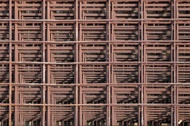 Reinforcing iron mesh stacked on top of each other and forming a pleasing symmetrical pattern, industrial background idea with metal rods fabric used in strengthening built structures or concrete work.