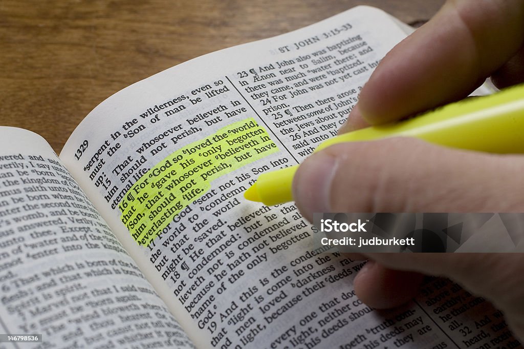 Bible Study, John 3:16 A man uses a highlighter to mark a bible verse, John 3:16. Bible Stock Photo