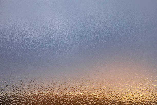 Window with drops sun set on the horizon.