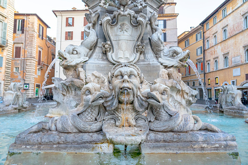 sculpture of a human head gushing liquid from the mouth of a water fountain in front of the pantheon in the Italian city of Rome.