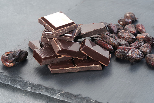 Broken dark chocolate and cocoa beans on a table