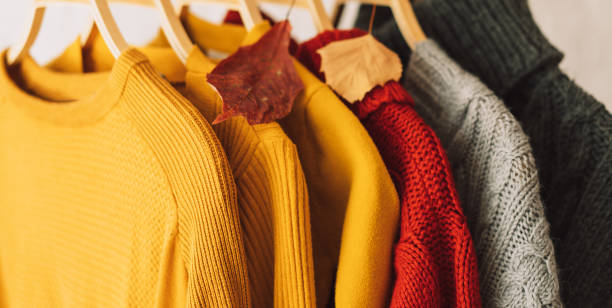 istock Multi-colored knitted sweaters on wooden hangers hang on an iron rack rale 1467993660