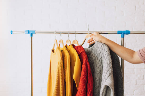istock Multi-colored knitted sweaters on wooden hangers hang on an iron rack rale 1467993667