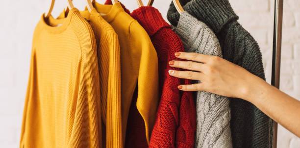 istock Multi-colored knitted sweaters on wooden hangers hang on an iron rack rale 1467993673