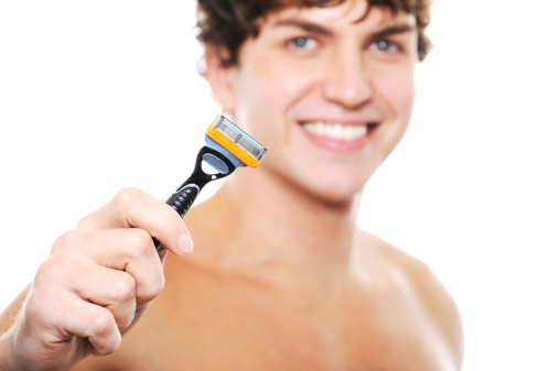 Happy laughing clean-shaven face of young man with razor in the hand  on foreground