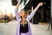 Blonde businesswoman in purple suit having fun walking and appreciating beautiful warm day after work