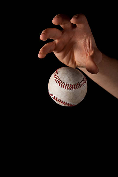 Man's Hand Dropping a Baseball stock photo