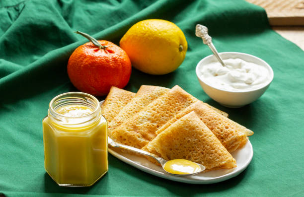 Pancakes served with fruit curd and sour cream, a traditional meal for Maslenitsa and Carnival.