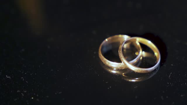 Two wedding rings lie on the table and illuminated by a bright beam of light.