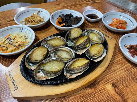 Korean-style grilled abalone and various side dishes.