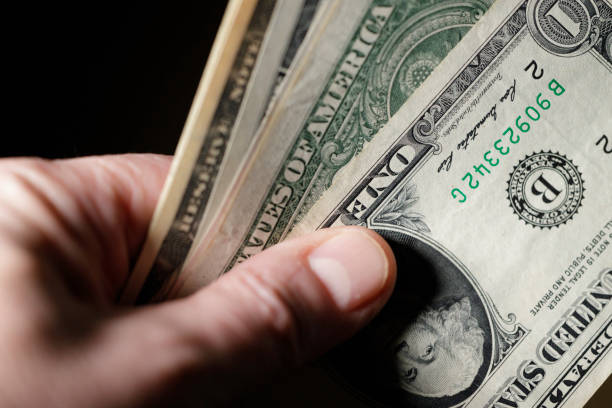 istock mature man holding US Dollar bills 1468014095