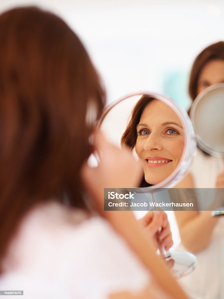 Lächelnde Frau, die Ihr Gesicht im Spiegel im - Lizenzfrei Spiegel Stock-Foto