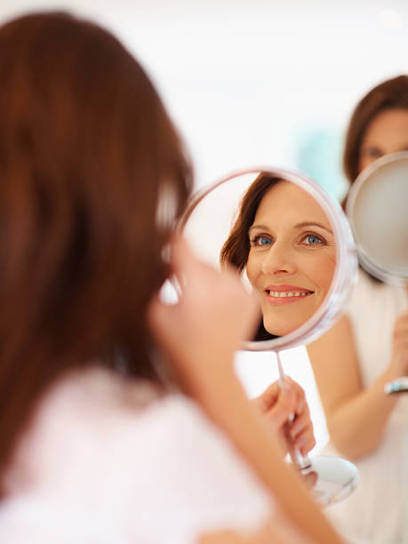 istock Smiling lady looking at her face in mirror 146801675