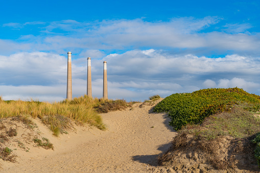 The three 450’ smoke stacks at Morro Bay, California. They can be seen towering over the sand dune landscape.