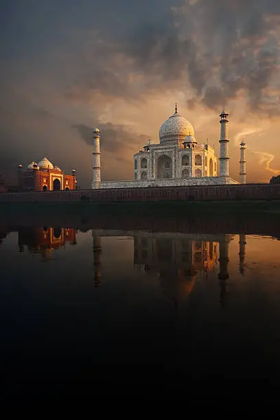 The iconic Taj Mahal and sunset sky beautifully reflected in the calmly flowing Jamuna river.