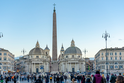 square with an obelisk centered and framed between the two domes of the church of santa maria de Popolo, Rome.