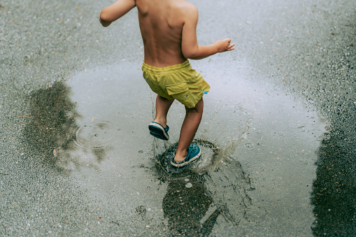 Photo of a young boy who enjoys summer rain and puddles