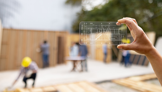 Close-up on an architect at a construction site looking at a blueprint using an interactive screen