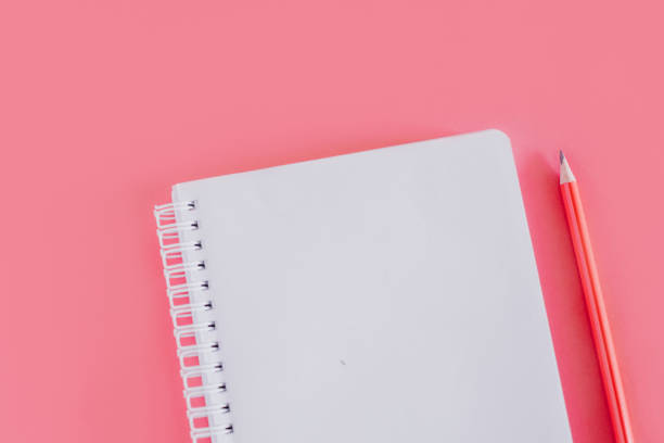 istock Notebook with a blank page and a pencil on pink background. 1468025233