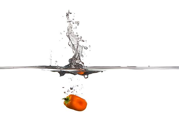 Orange Bell Pepper falling into water splash stock photo