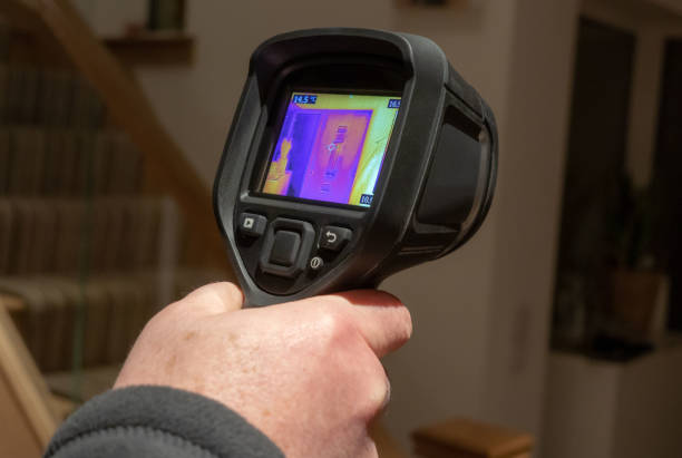 Handheld infrared thermal camera being used A male surveyor using a handheld infrared thermal camera, to inspect the interior of a domestic home, looking for heat anomalies. The camera viewfinder shows a coloured thermal image with varying temperature ranges. thermal image stock pictures, royalty-free photos & images