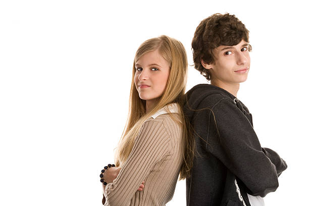 Teenage couple standing with arms crossed Teenage couple standing back to back with arms crossed 15 year old blonde girl stock pictures, royalty-free photos & images