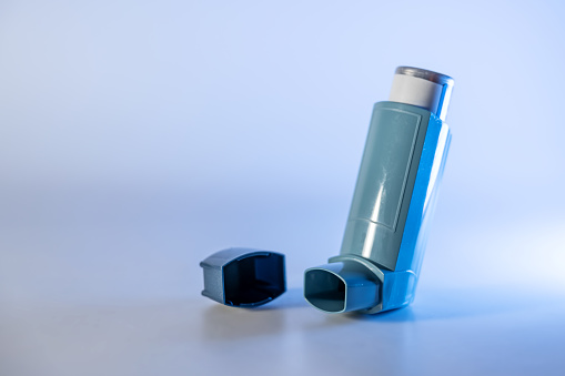 Blue inhaler, also known as pump or allergy spray, medical device for asthma or COPD patients, copy space, selected focus, narrow depth of field