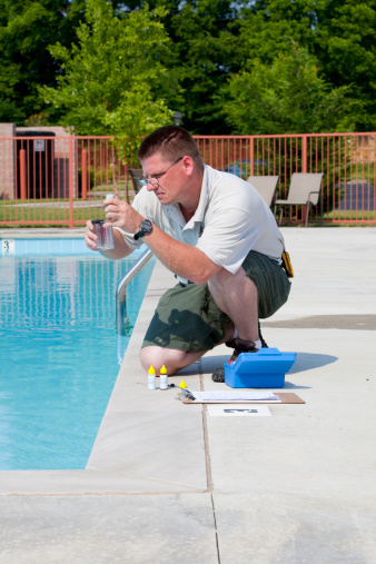 Service man checking chlorine, PH and other chemical levels in community pool