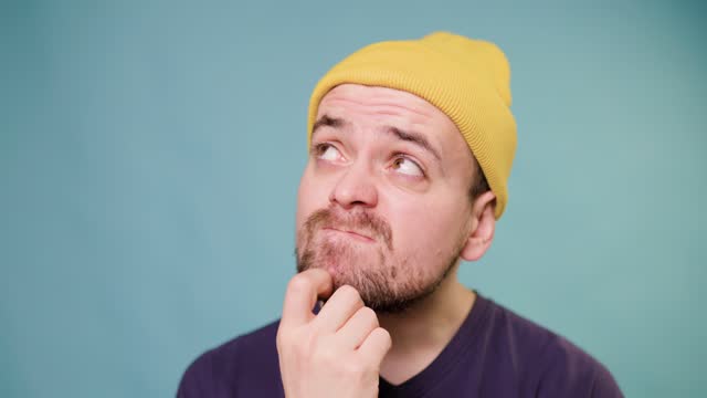 A studio shot of a male guy with a confused expression, making a funny face, as if he's