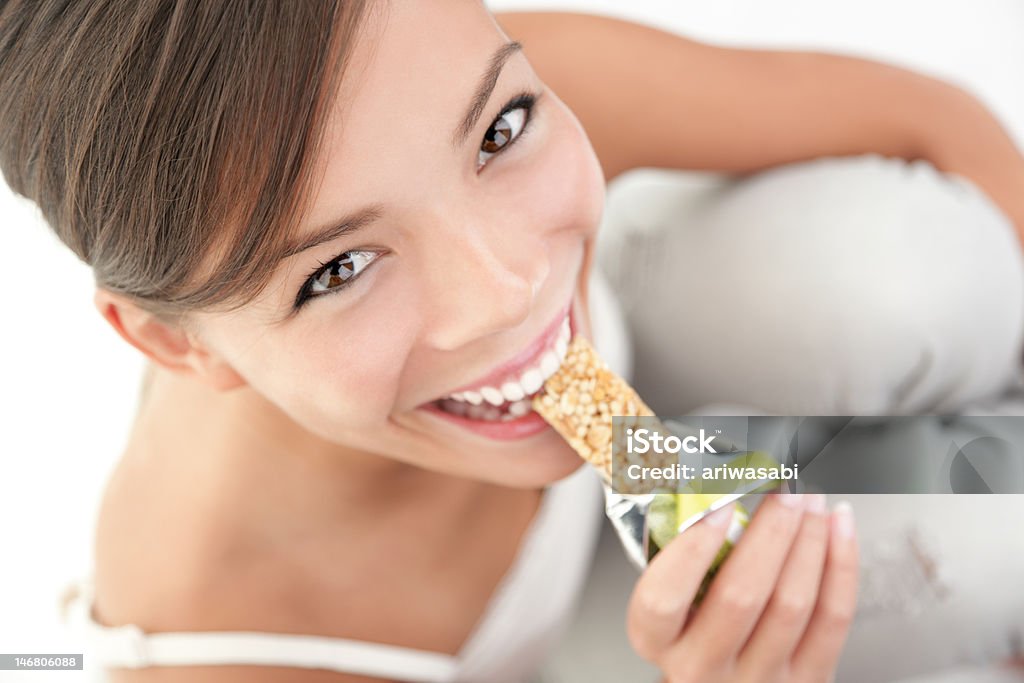 Snack eating woman Young woman asian caucasian eating healthy muesli bar.Click for more: Protein Bar Stock Photo